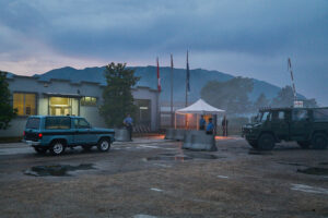 Scena esterna della serie The Swarm con checkpoint militare e veicoli all’ingresso di una base, fotografia di Stefano Delìa