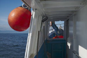 Dettaglio peschereccio con boa rossa | Most of Italy | Foto Stefano Delìa Dettaglio di un peschereccio con boa rossa e marinaio a bordo, fotografia documentaria di Stefano Delìa per Most of Italy