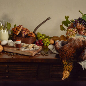 Natura morta con uva, pane, latte, uova e selvaggina su tavolo rustico, fotografia fine art food