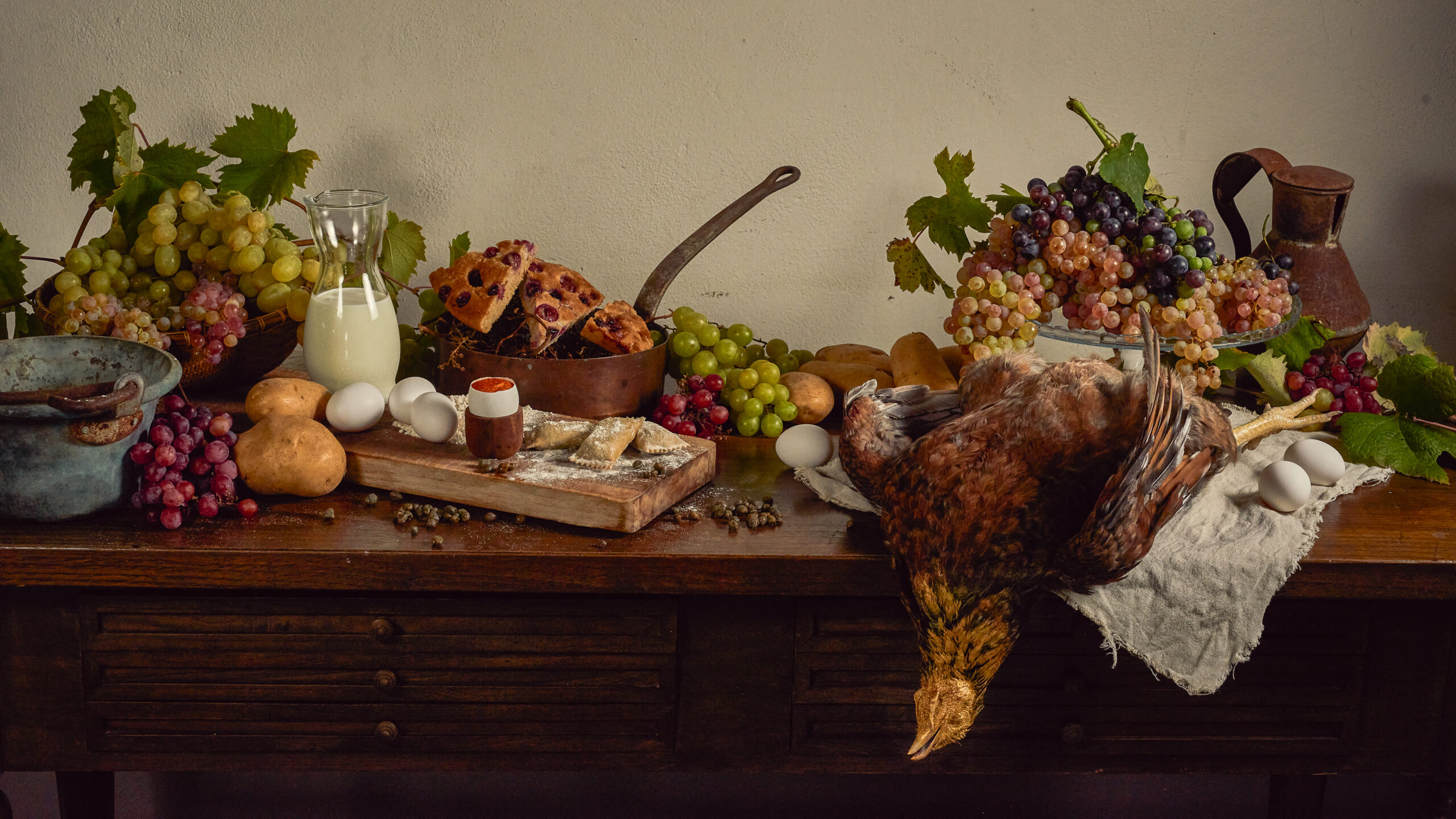 Natura morta con uva, pane, latte, uova e selvaggina su tavolo rustico, fotografia fine art food